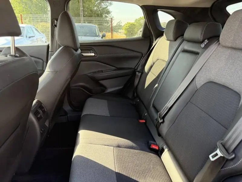 Vue intérieure côté droit de la banquette arrière noire en tissu et cuir du Nissan Qashqai 2025, avec ceintures et appuie-têtes.