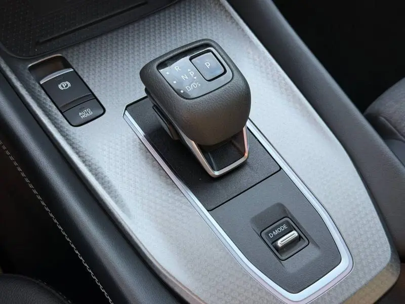 Gros plan sur la console centrale du Nissan Qashqai 2025, avec levier de vitesse automatique et bouton D-MODE.