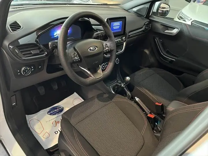 Intérieur avant droit du Ford Puma 1.0 EcoBoost hybride 2022 avec volant multifonction et sellerie noire à surpiqûres rouges.