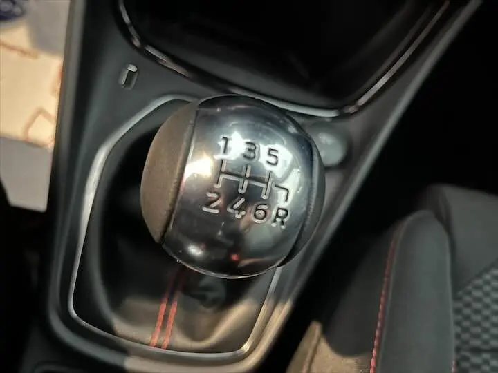 Le levier de vitesses manuel en gros plan dans l'habitacle du Ford Puma avec coutures rouges sur le soufflet.