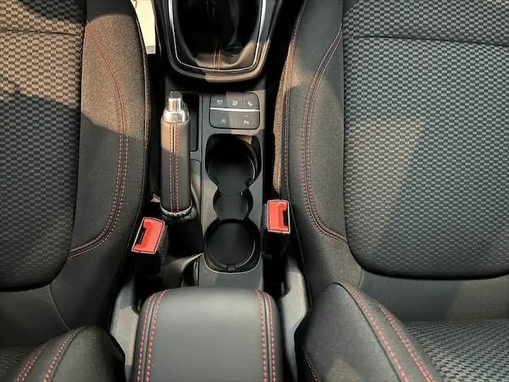 Vue de dessus de la console centrale du Ford Puma blanc glacier 2022 avec sièges noirs à surpiqûres rouges et frein à main manuel.