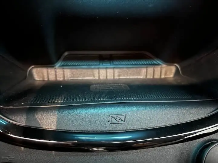 Gros plan sur le compartiment de recharge sans fil avec symbole batterie dans l'habitacle du Ford Puma blanc glacier.