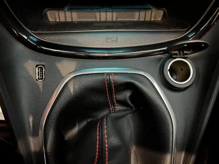 Gros plan sur la console centrale du Ford Puma blanc glacier, mettant en valeur le soufflet de levier de vitesses noir avec surpiqûres rouges.