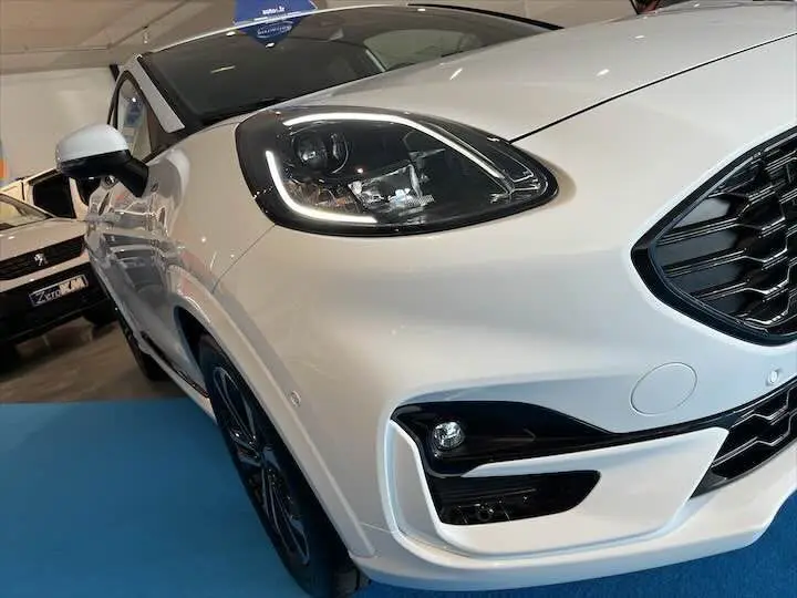 Vue 3/4 avant gauche d'un Ford Puma blanc glacier avec phares LED et calandre noire brillante.