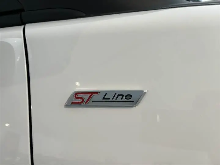 Gros plan sur l'écusson ST Line rouge et argent sur la porte blanche glacée d'une Ford Puma 2022.