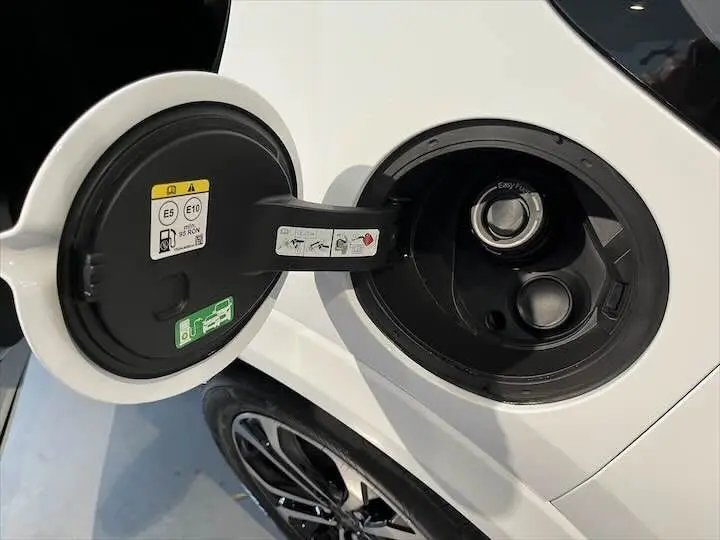 Gros plan sur la trappe à carburant ouverte du Ford Puma blanc glacier, avec la roue arrière et jante visible en arrière-plan.