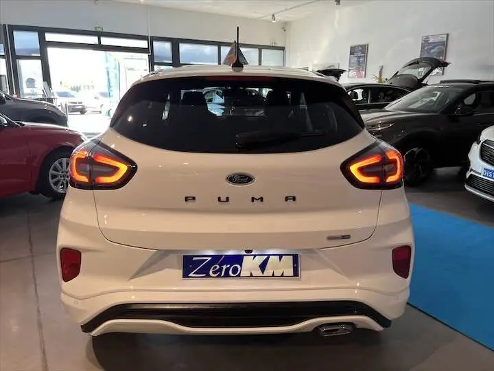 Vue arrière d'un Ford Puma blanc glacier avec feux arrière allumés dans un showroom.