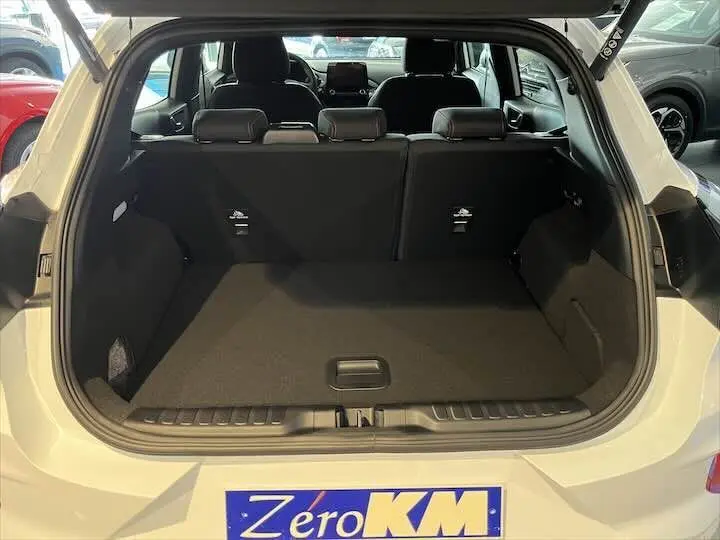 Coffre ouvert vu de l'arrière d'un Ford Puma blanc glacier, montrant l'espace de chargement et les sièges arrière.