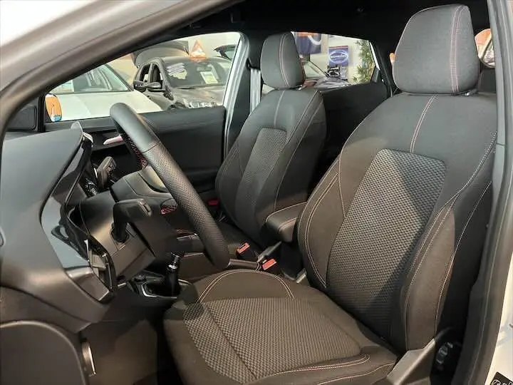 Intérieur du Ford Puma 2022 blanc glacier, vue côté conducteur montrant sièges noirs avec surpiqûres rouges et volant cuir.