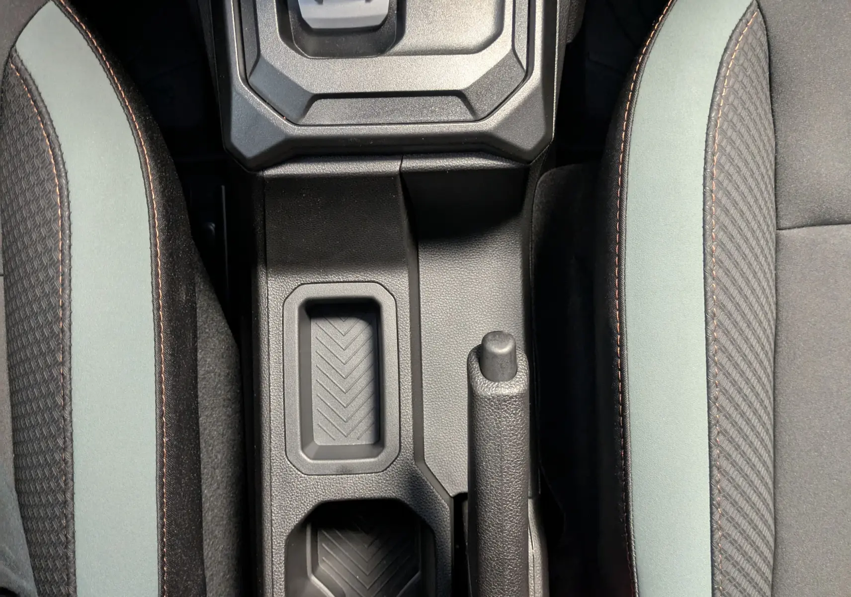 Vue plongeante sur la console centrale du Dacia Duster 1.6 Hybrid 140 Extreme avec levier de vitesse et sièges bicolores gris schiste.