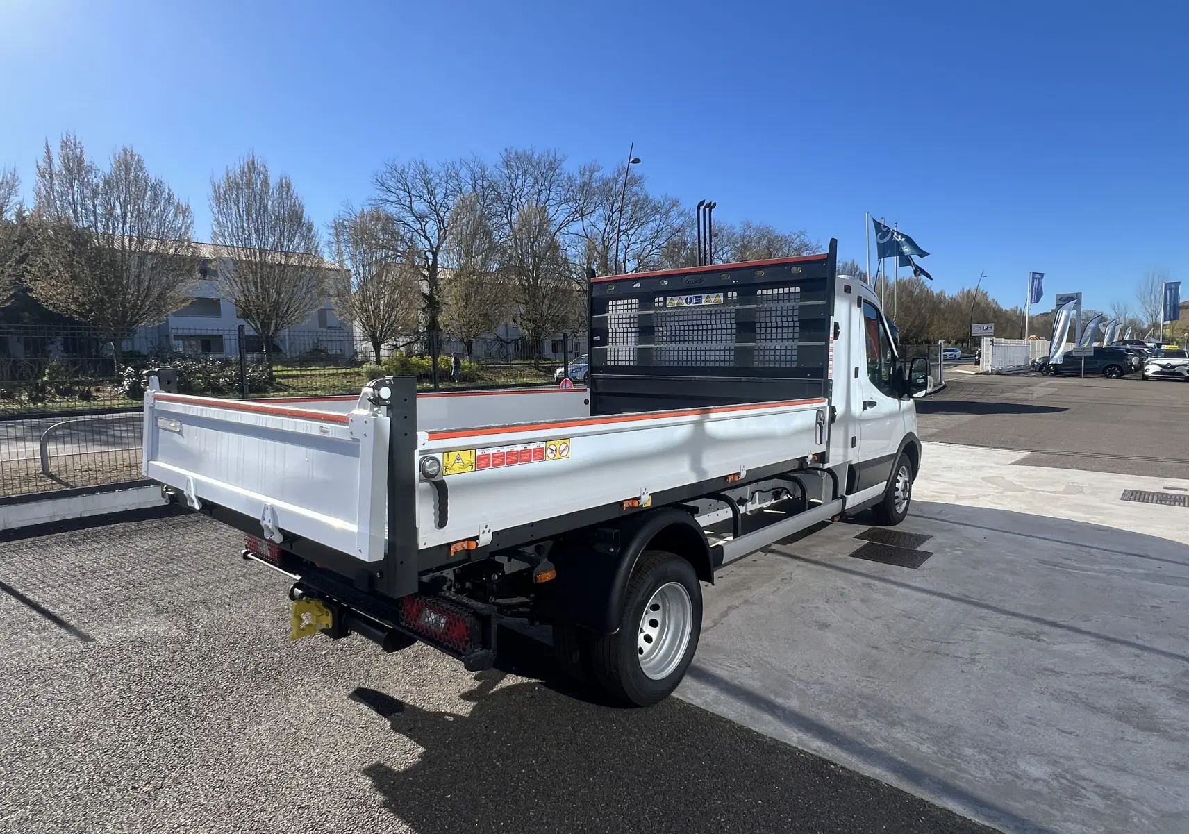 Ford Transit Chassis cabine blanc vu 3/4 arrière droit avec benne et coffre, roues jumelées et pare-éclats noir.