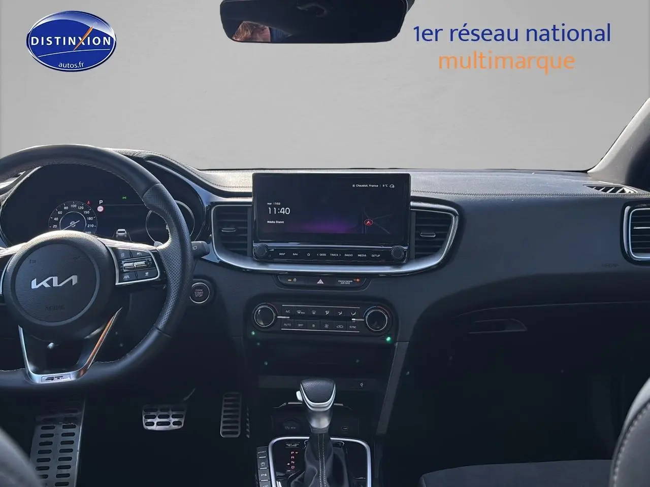 Vue intérieure frontale du tableau de bord noir du KIA Xceed 2024 avec écran tactile et volant multifonction cuir.