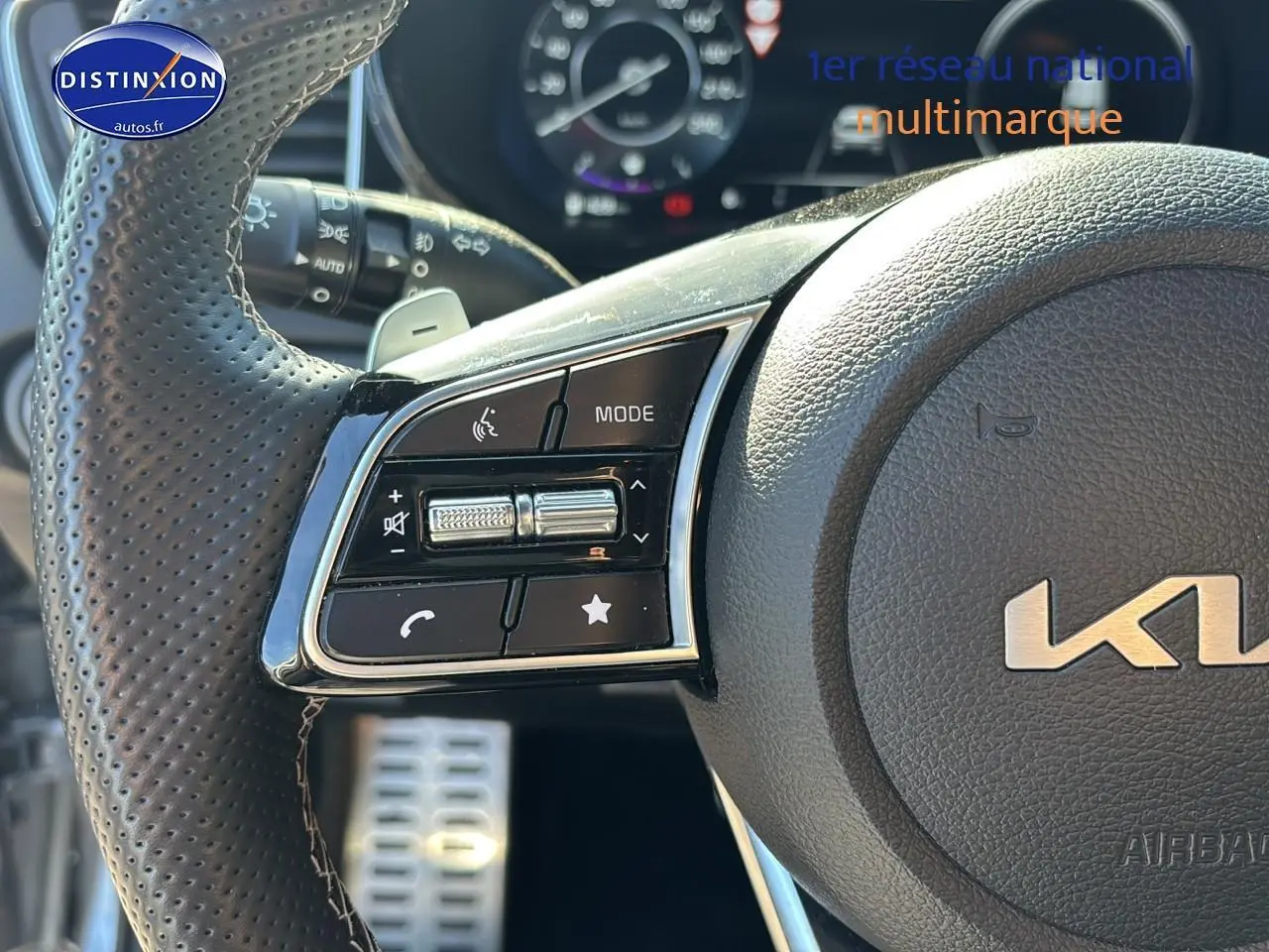 Gros plan sur le volant cuir perforé de la KIA Xceed 2024 avec commandes multifonctions et palettes au volant.