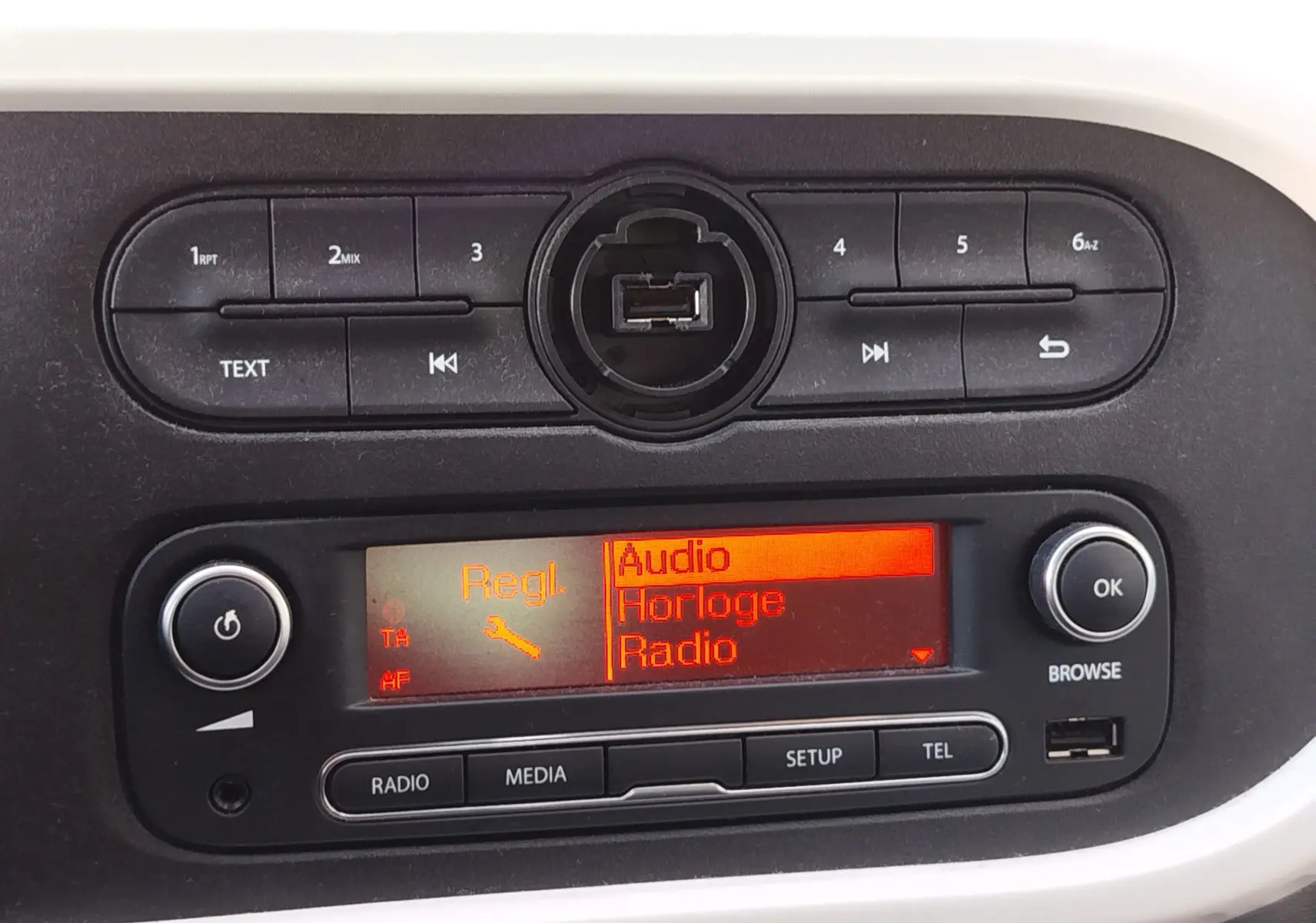 Gros plan sur la console centrale noire de la Renault Twingo Blanc Cristal 2016, affichage orange du menu audio.