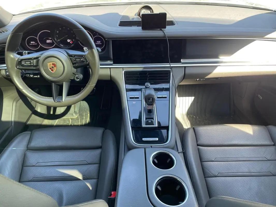 Vue intérieure du tableau de bord et console centrale du Porsche Panamera gris, avec volant multifonctions et écran tactile éteint.