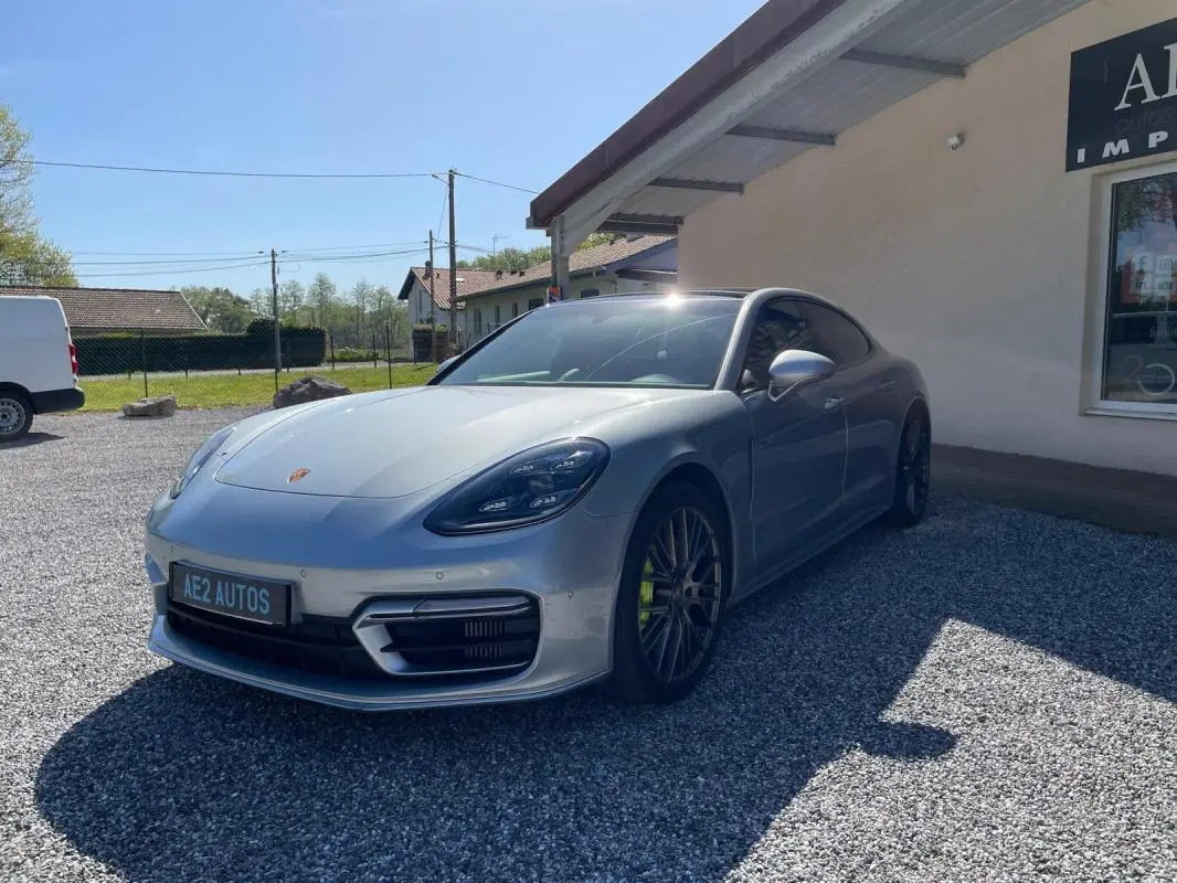 Porsche Panamera 4 V6 Hybrid gris vue 3/4 avant droit, avec jantes noires et étriers de frein verts.