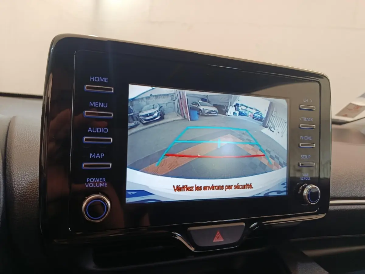 Écran tactile central montrant la caméra de recul avec guidage de trajectoire dans une Toyota Yaris blanche hybride.