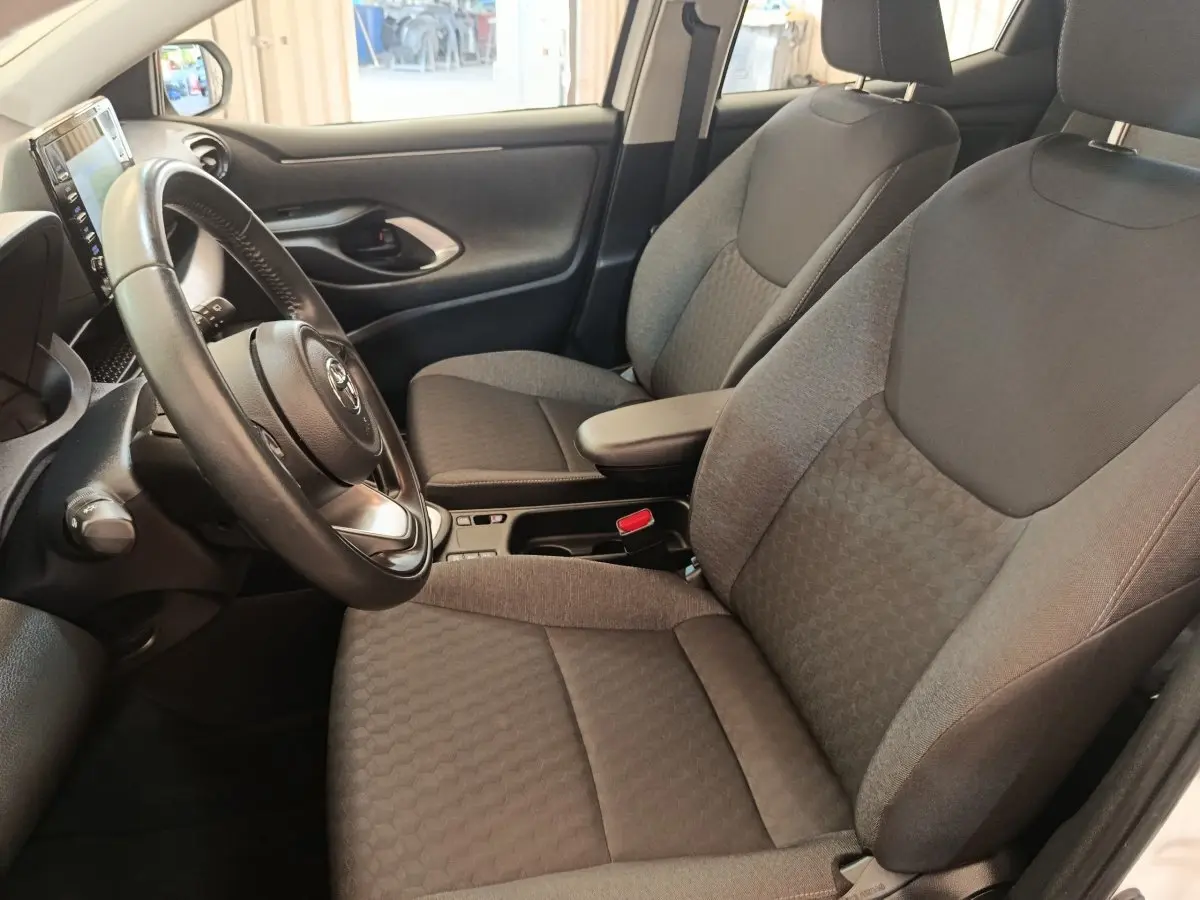 Intérieur de la Toyota Yaris hybride 2022 vu côté conducteur, sièges tissu gris et volant cuir multifonctions.