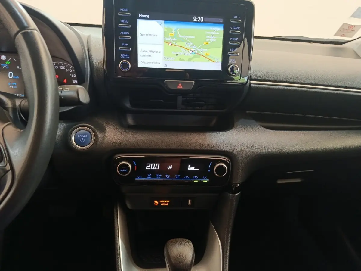 Vue intérieure centrée sur la console centrale de la Toyota Yaris hybride 2022 avec écran tactile et commandes climatisation.
