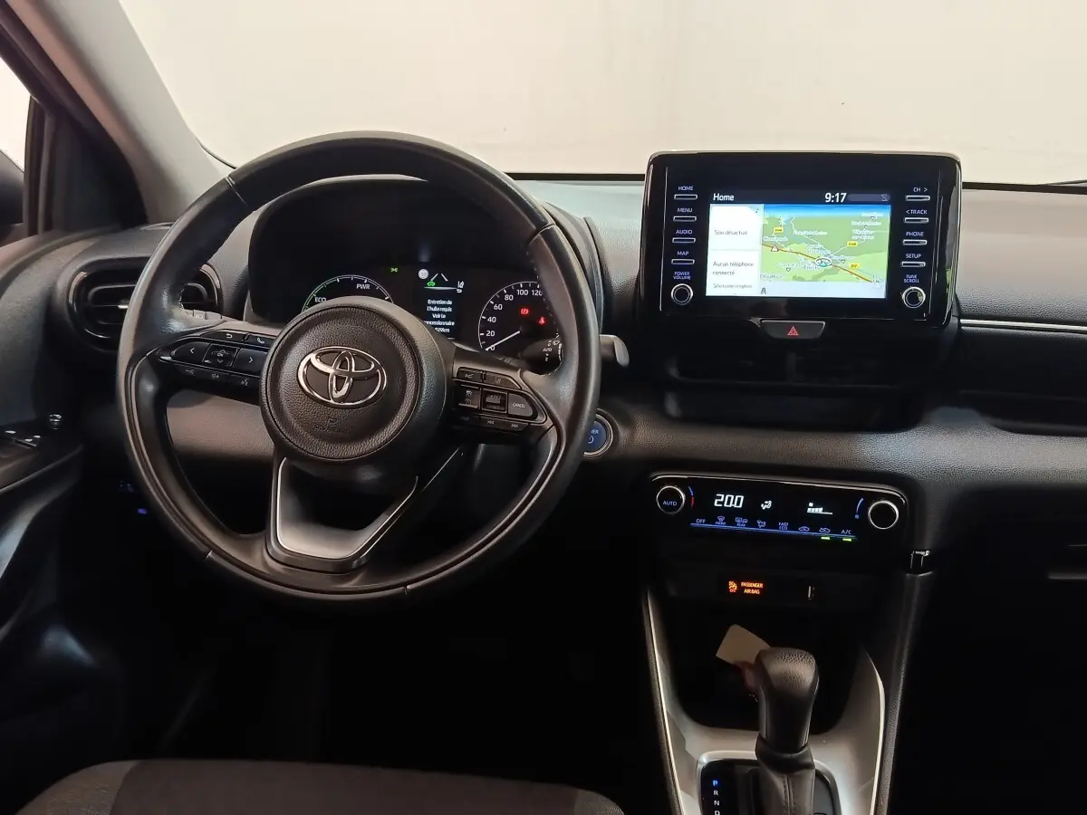 Vue intérieure centrée sur le volant cuir multifonctions et l’écran tactile du tableau de bord de la Toyota Yaris hybride 2022.