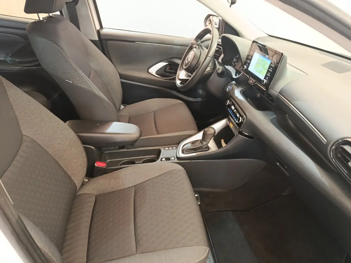 Vue intérieure côté conducteur de la Toyota Yaris hybride 2022, montrant sièges tissu gris et tableau de bord avec écran tactile.
