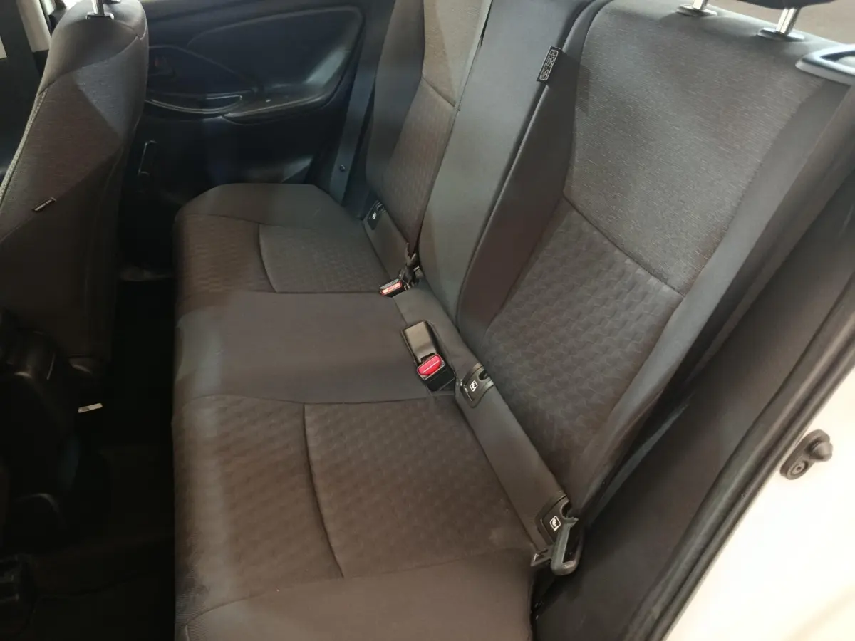 Vue côté droit de la banquette arrière noire de la Toyota Yaris hybride blanche 2022 avec ceintures et appuie-têtes visibles.