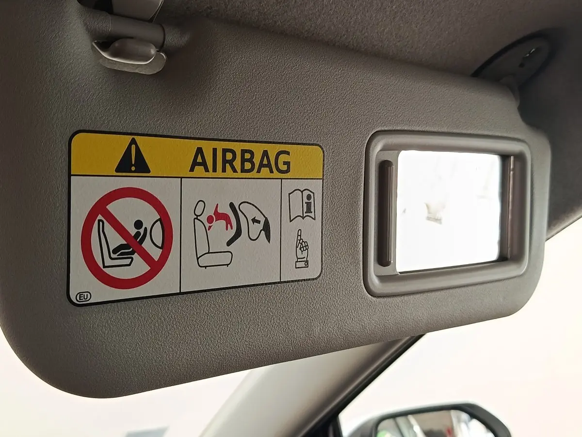 Détail du pare-soleil côté conducteur de la Toyota Yaris blanche 2022 avec miroir et avertissement airbag visible.