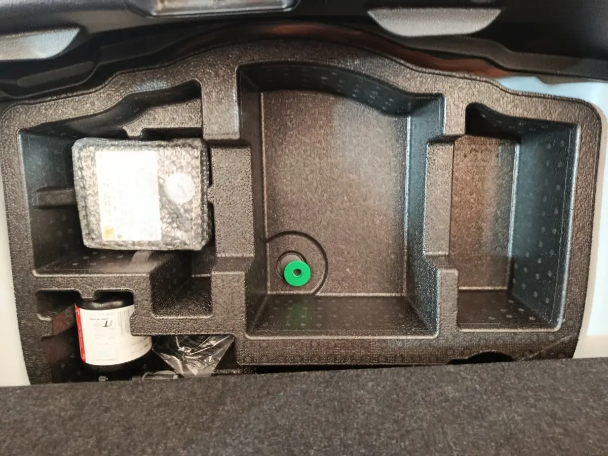 Rangement en mousse noire dans le coffre d'une Toyota Yaris hybride blanche, vue de dessus, sans objets visibles.