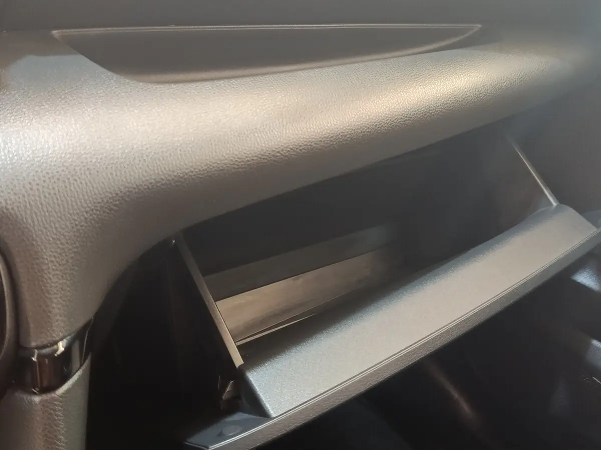 Gros plan sur la boîte à gants ouverte de la Toyota Yaris Hybride 116h Dynamic Business Beyond Zer, intérieur noir.
