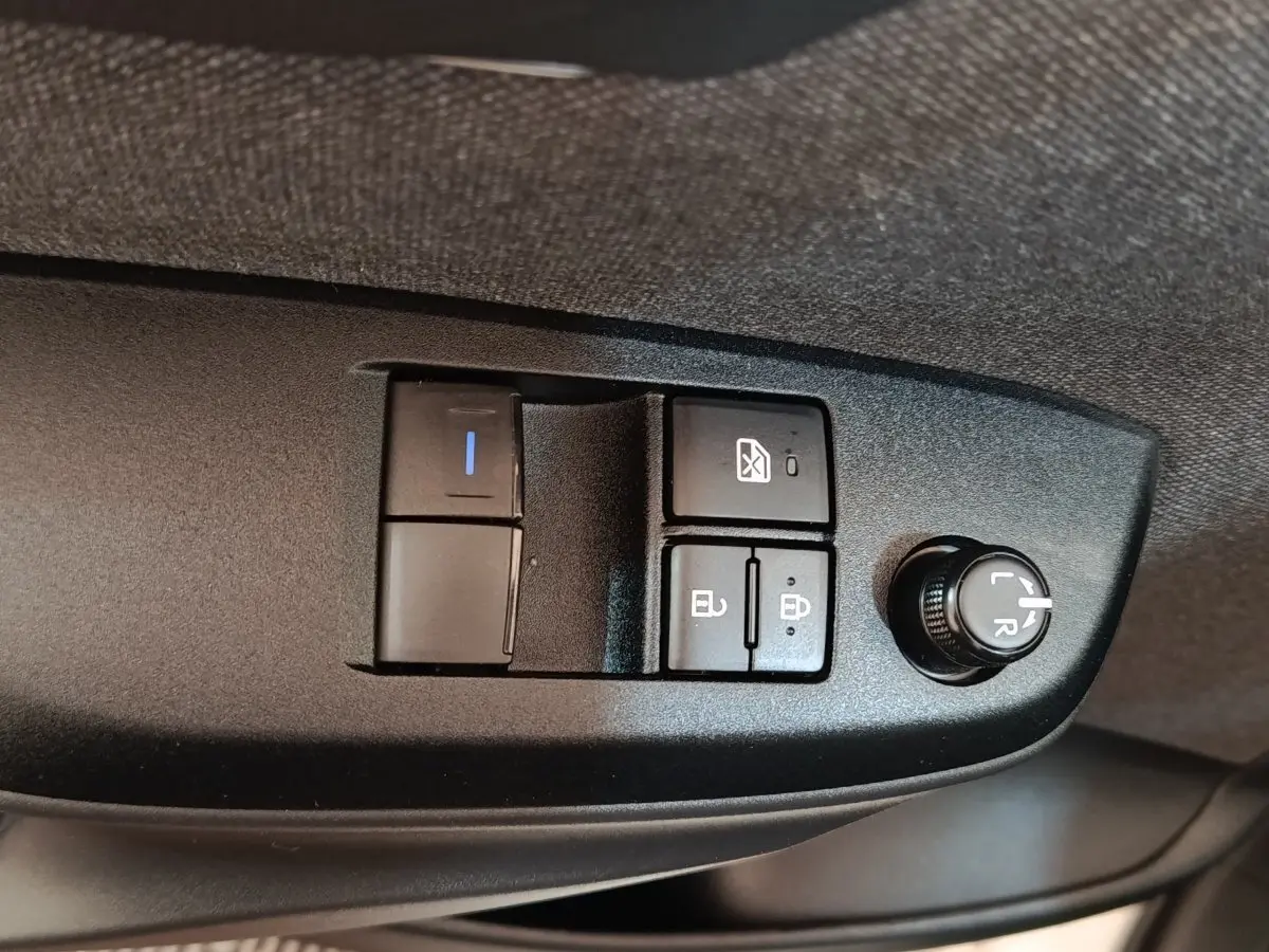 Gros plan sur les commandes de réglage des rétroviseurs et des vitres côté conducteur de la Toyota Yaris blanche hybride 2022.