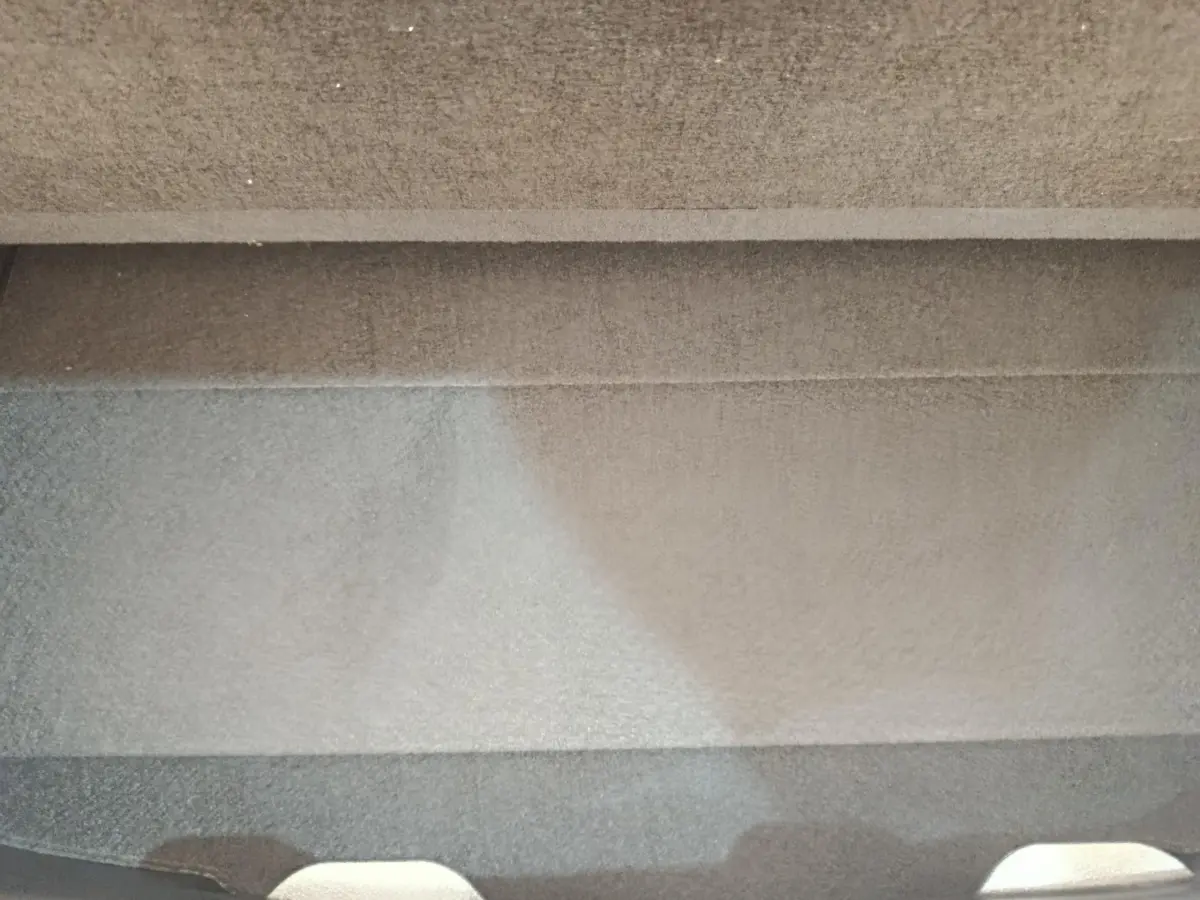 Vue arrière en léger contre-plongée d'une Toyota Yaris hybride blanche, avec spoiler de coffre visible.