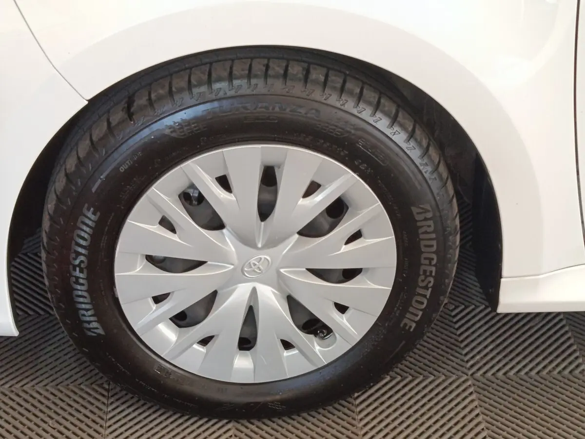 Gros plan sur la roue avant droite blanche d'une Toyota Yaris hybride 2022 avec enjoliveur gris et pneu Bridgestone.