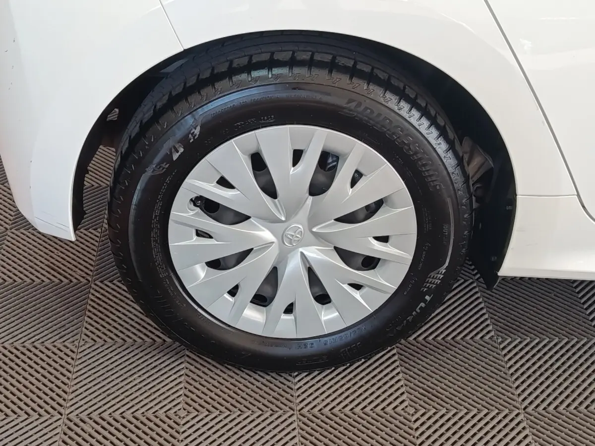 Gros plan sur la roue avant gauche blanche d’une Toyota Yaris hybride 2022 avec enjoliveur gris et pneu Bridgestone.