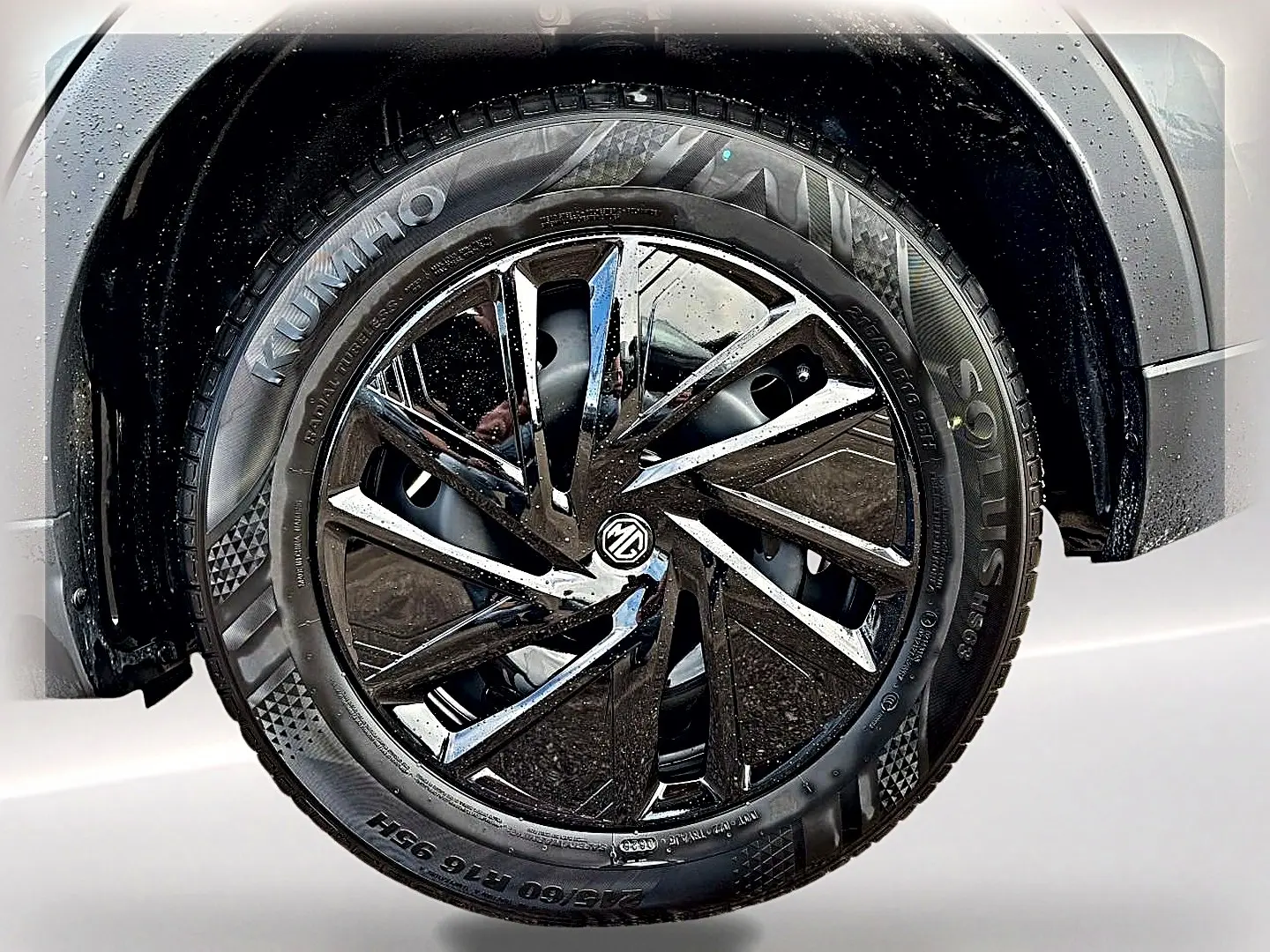 Gros plan sur la roue avant droite du MG ZS Camden grey, jante alliage noire brillante avec logo MG au centre.
