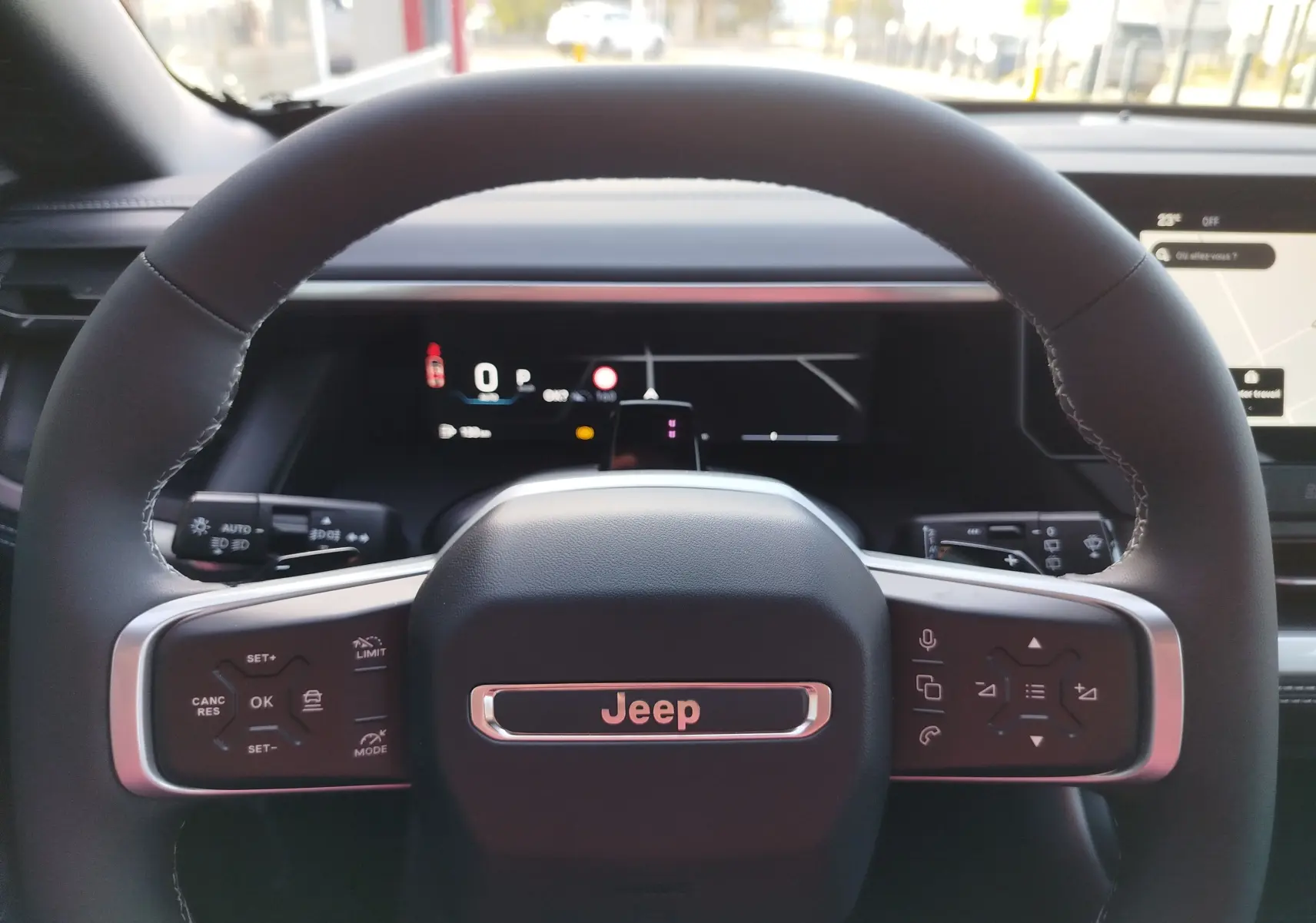 Vue rapprochée du volant noir du Jeep Compass 2026, avec commandes intégrées et tableau de bord numérique en arrière-plan.
