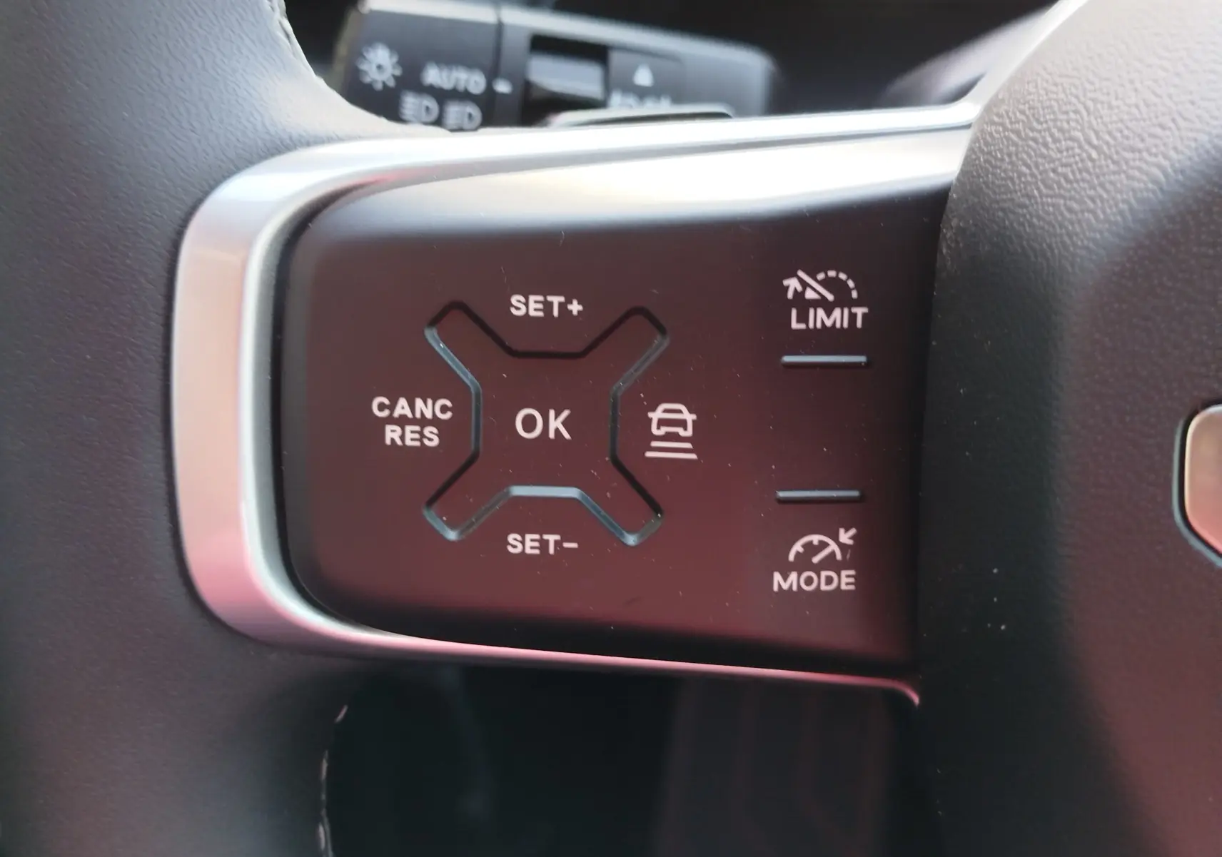 Gros plan sur les commandes au volant du Jeep Compass noir Vulcano, avec boutons de régulateur de vitesse et limiteur.
