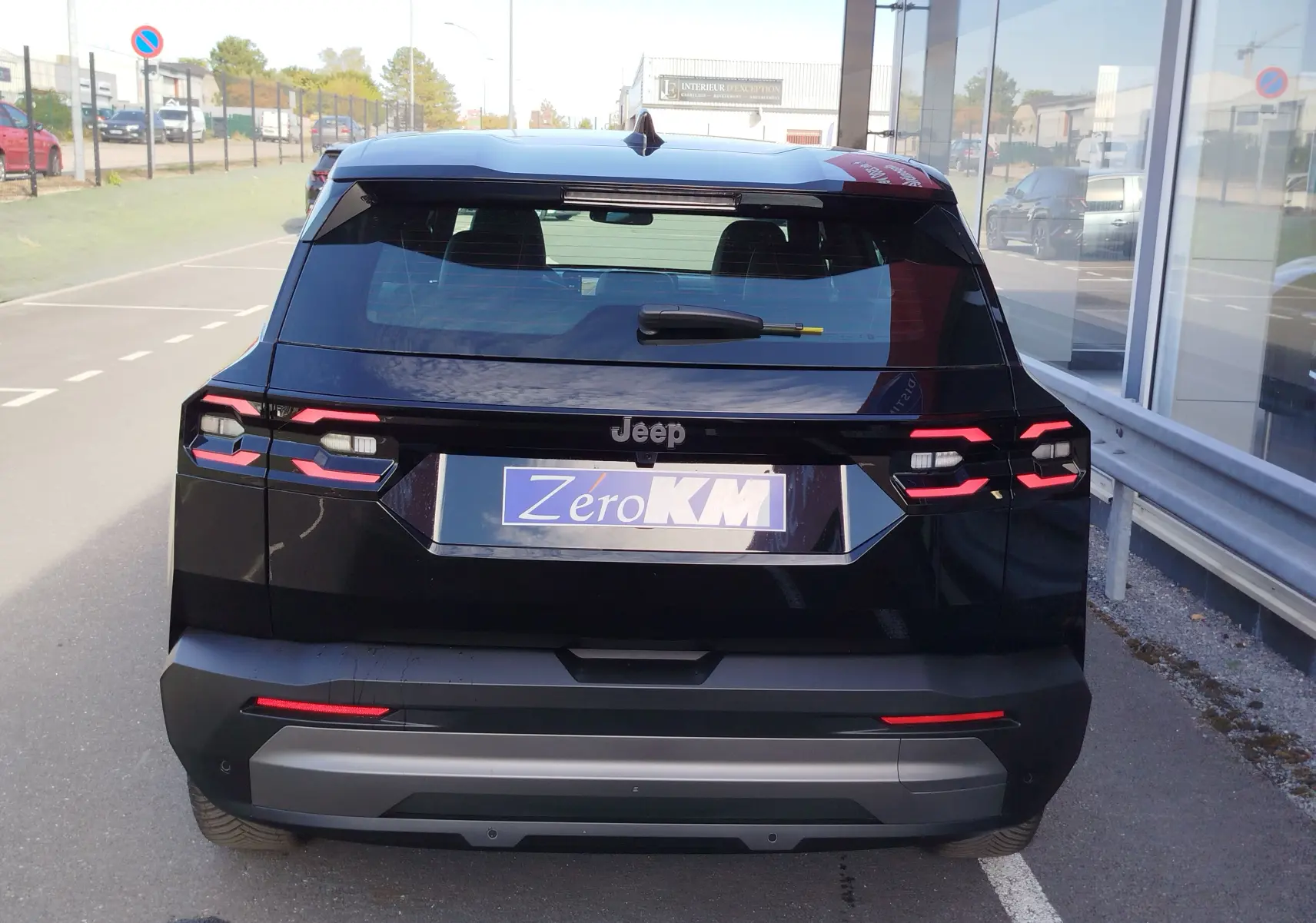 Vue arrière d'un Jeep Compass noir Vulcano Metal 2026 avec feux arrière LED et logo Jeep visible sur un parking.
