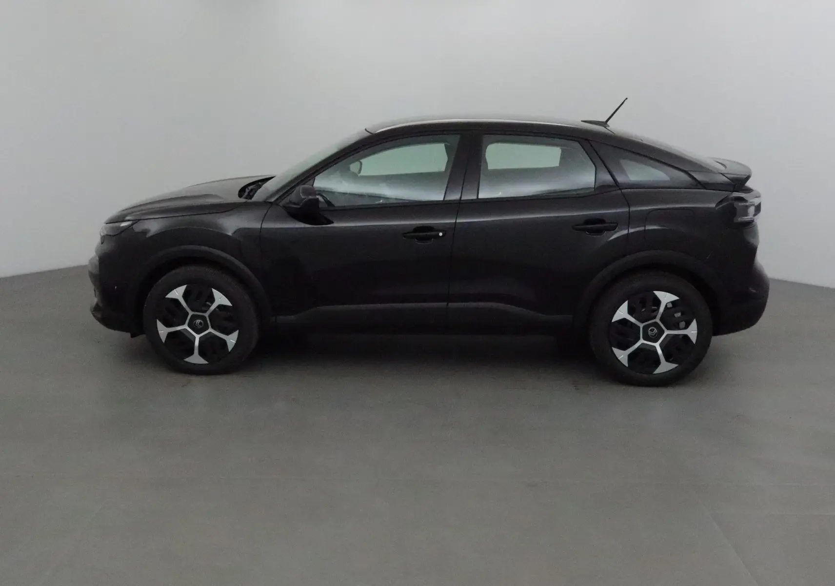 Profil côté gauche d'une Citroën C4 noire 2025 avec jantes au design moderne et toit légèrement incliné.