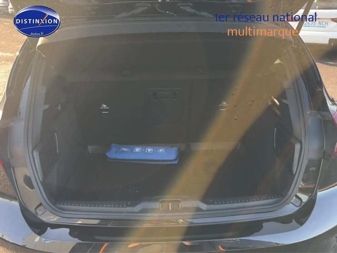 Coffre ouvert vu de l'arrière d'une Ford Focus noire 2024, avec tapis et trousse de secours bleue visible.
