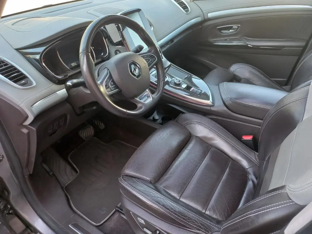 Vue intérieure côté conducteur du Renault Espace gris 2017, avec volant cuir et console centrale moderne.