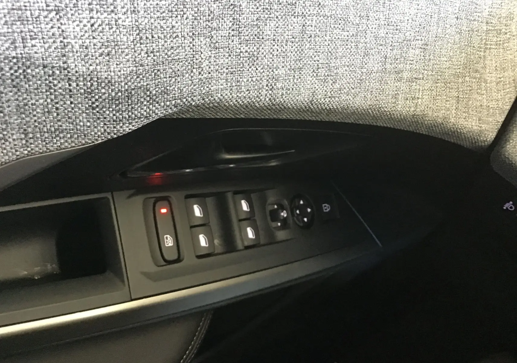 Gros plan sur les commandes des vitres et rétroviseurs côté gauche intérieur du Peugeot 3008 gris titane 2026.