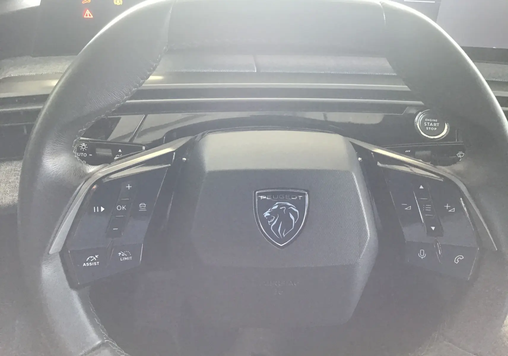 Vue rapprochée du volant cuir noir du Peugeot 3008 gris titane 2026, avec commandes multifonctions et bouton start/stop.