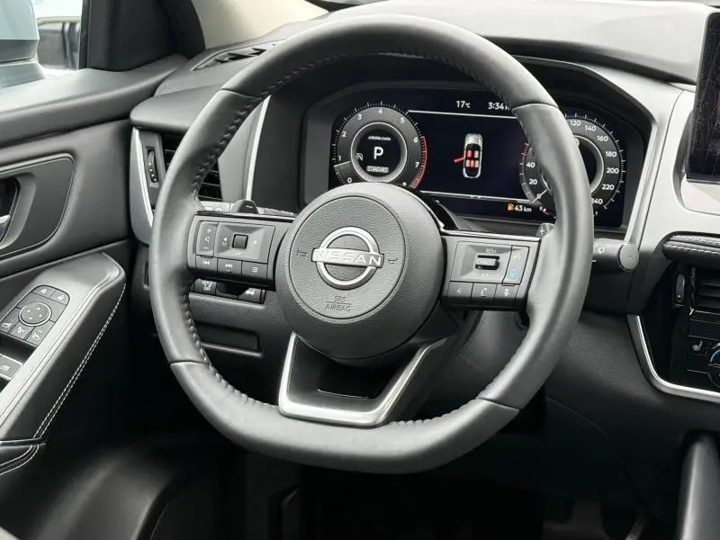 Vue rapprochée du volant cuir multifonction noir du Nissan Qashqai 2025 avec tableau de bord numérique et commandes intégrées.