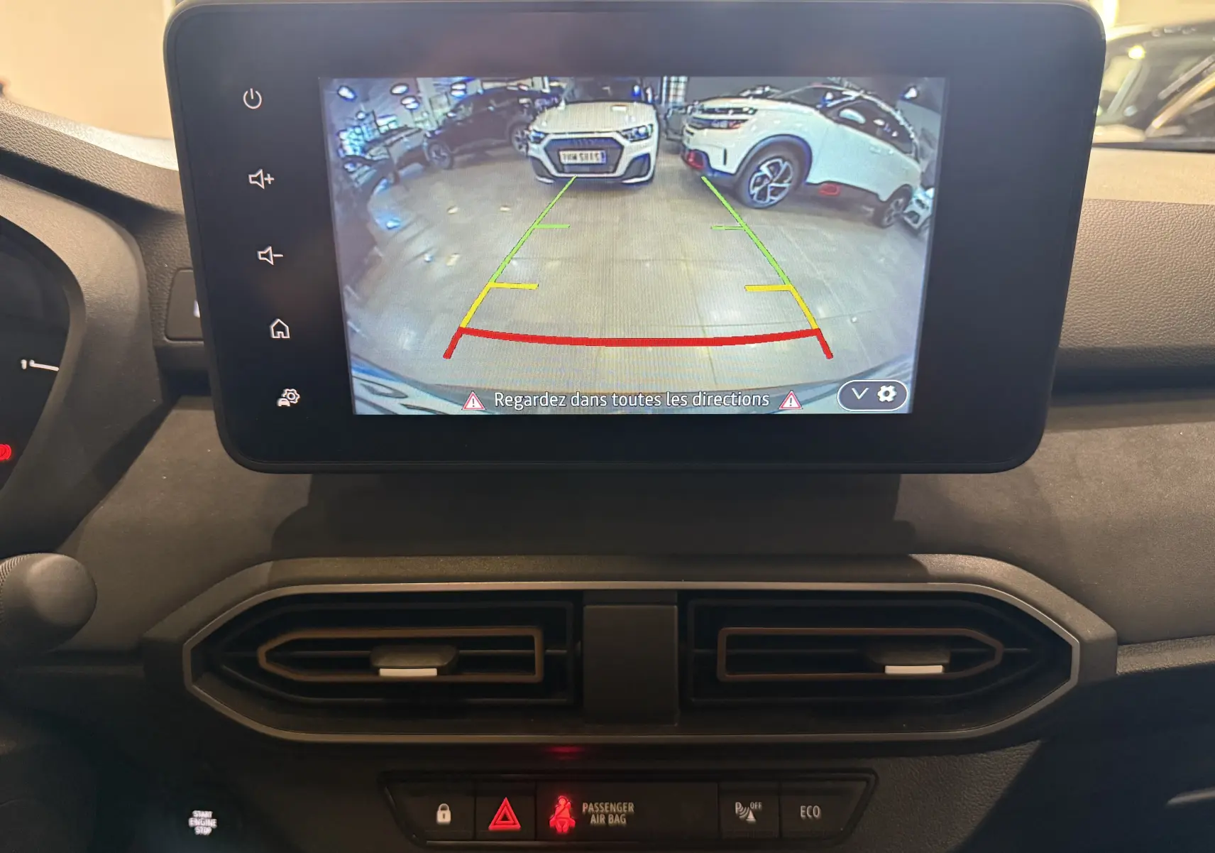 Écran central du Dacia Jogger Hybrid 140 Extreme montrant la caméra de recul avec vue sur un parking intérieur.