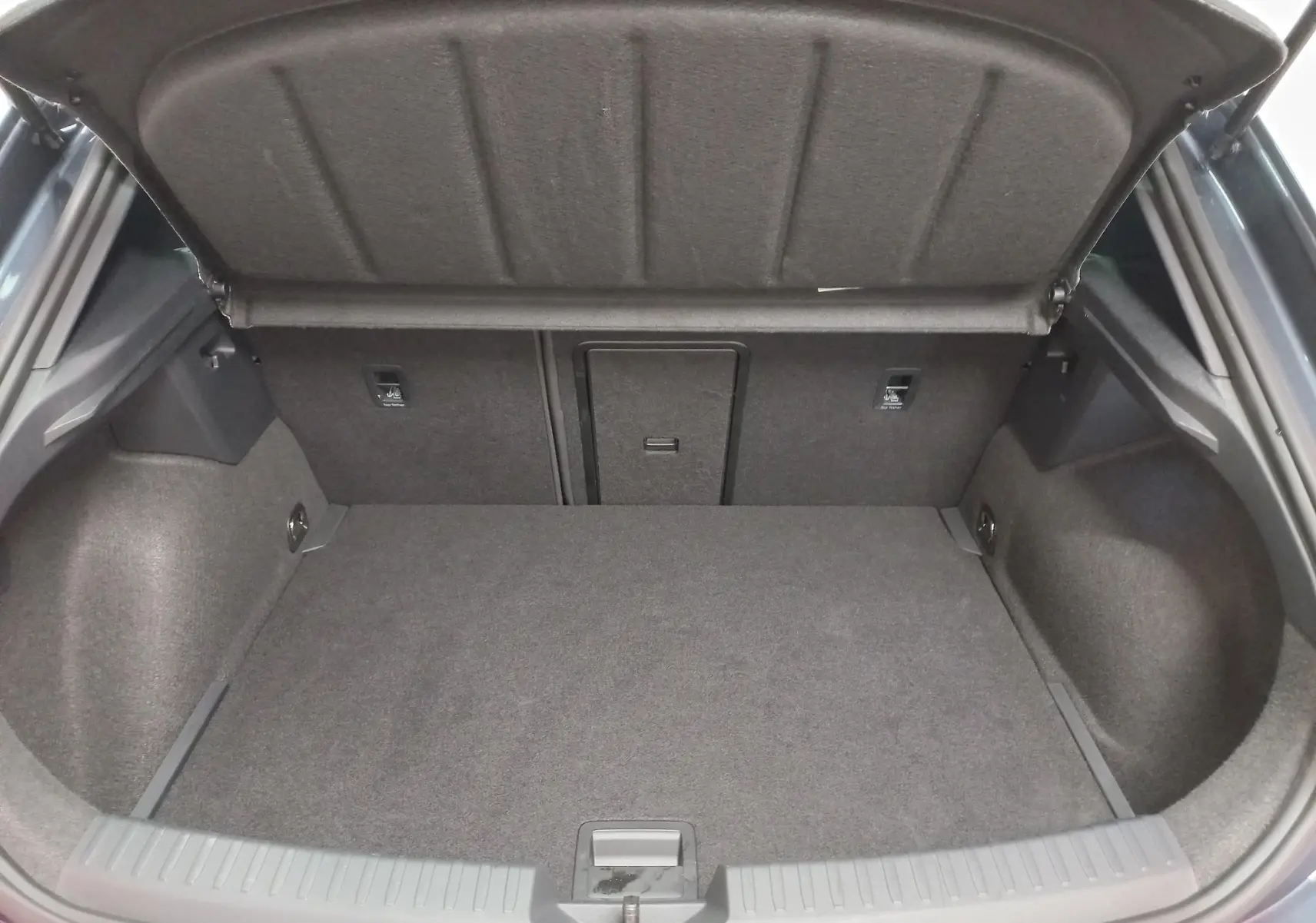 Coffre ouvert vu de l'arrière d'une CUPRA Leon Ph.2 gris magnétique, montrant l'espace de chargement vide et la moquette intérieure.