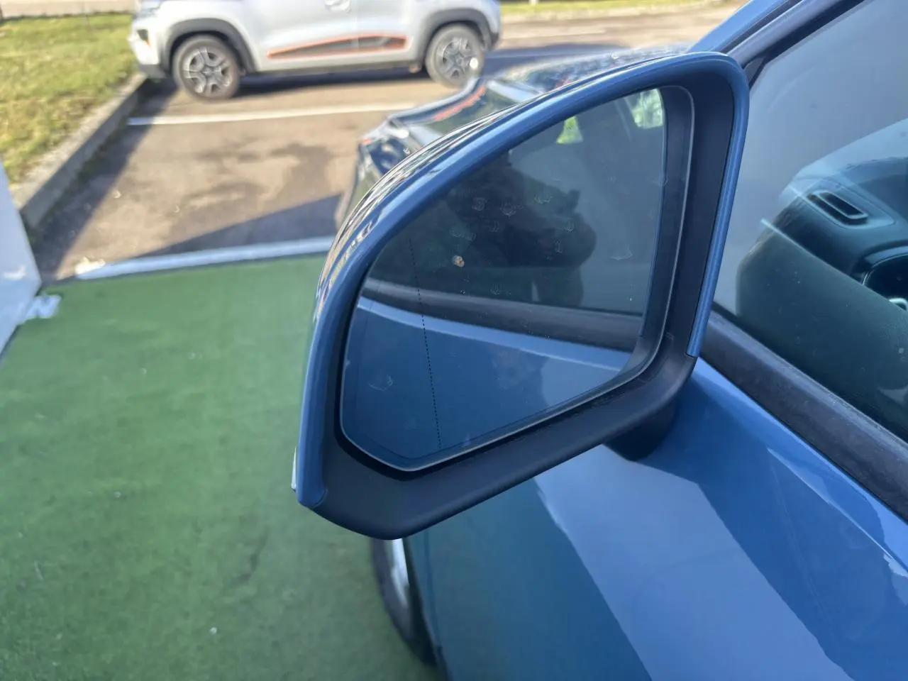 Rétroviseur extérieur droit bleu Fjord Blue d'un Volvo XC40 2024, avec partie de la portière visible.