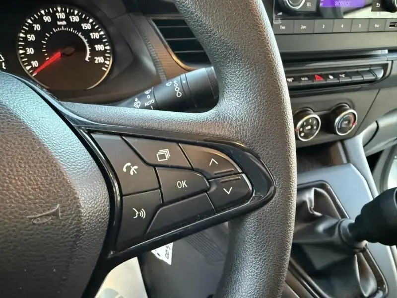 Gros plan sur le volant côté gauche du Renault Kangoo 2022 blanc, avec commandes intégrées et levier de vitesses manuel visible.