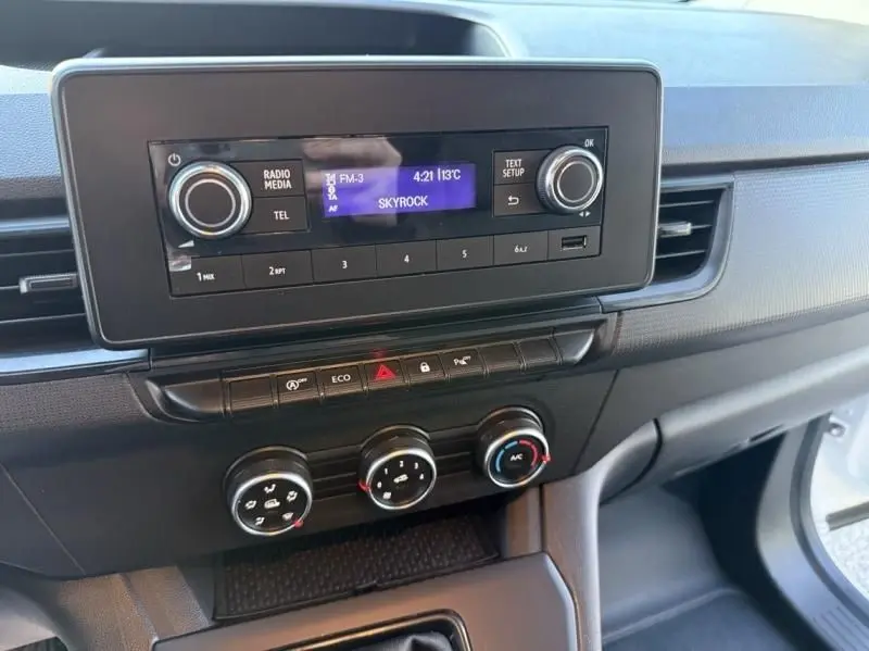 Vue rapprochée de la console centrale du Renault Kangoo blanc 2022, affichant la radio et les commandes de climatisation.