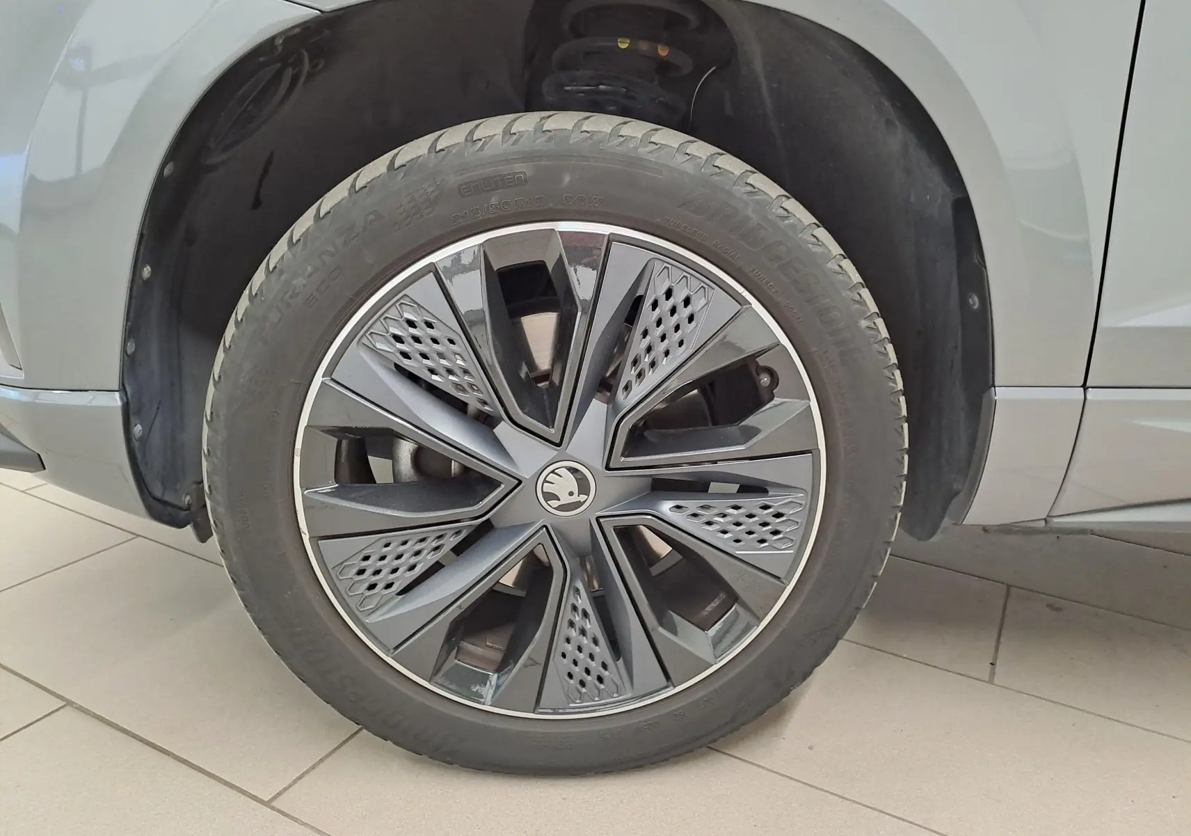 Gros plan sur la roue avant gauche du Skoda Karoq gris graphite 2025 avec jante design Sportline.
