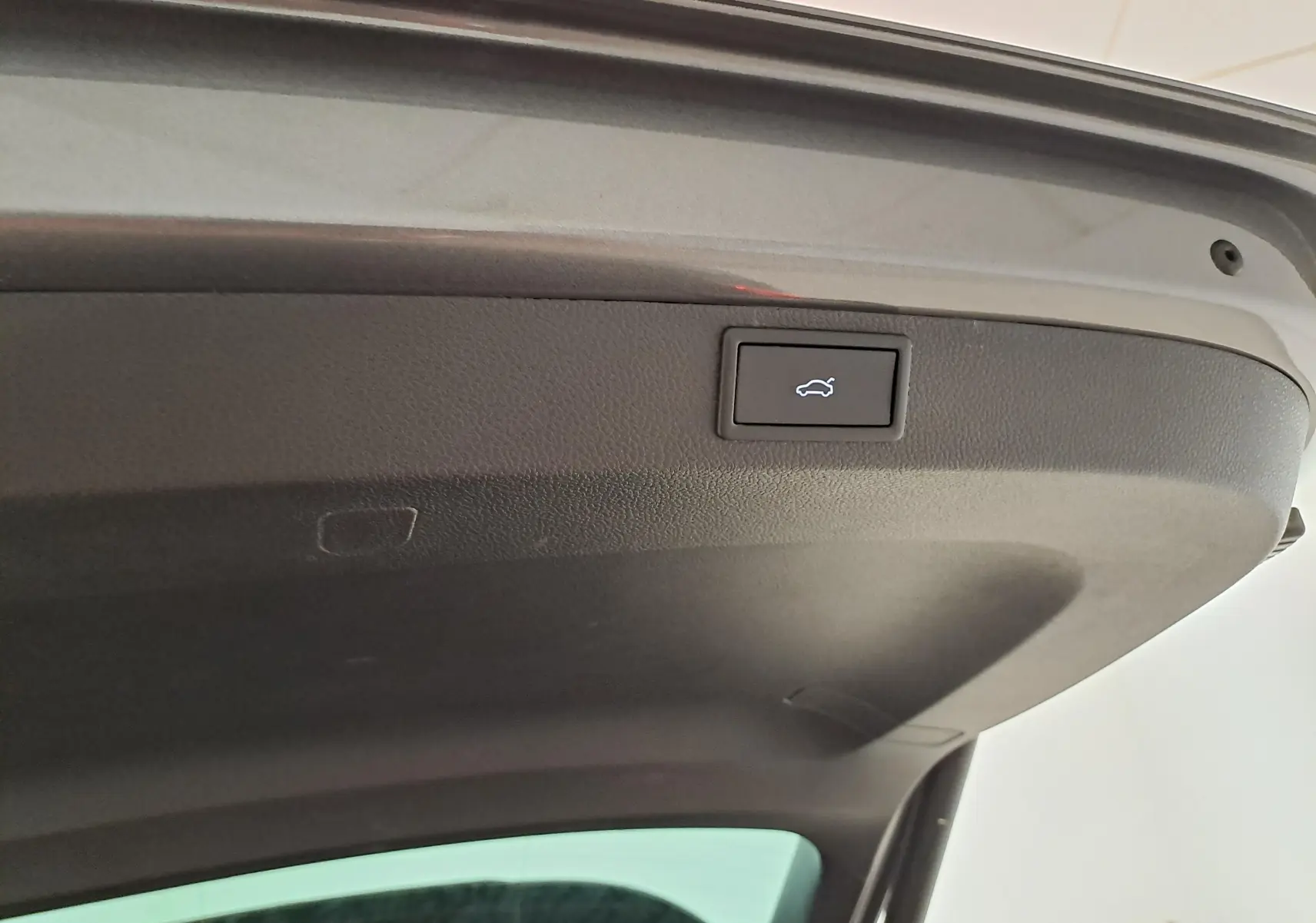 Détail du hayon électrique du SKODA KAROQ gris graphite 2025, bouton d'ouverture/fermeture avec icône coffre.